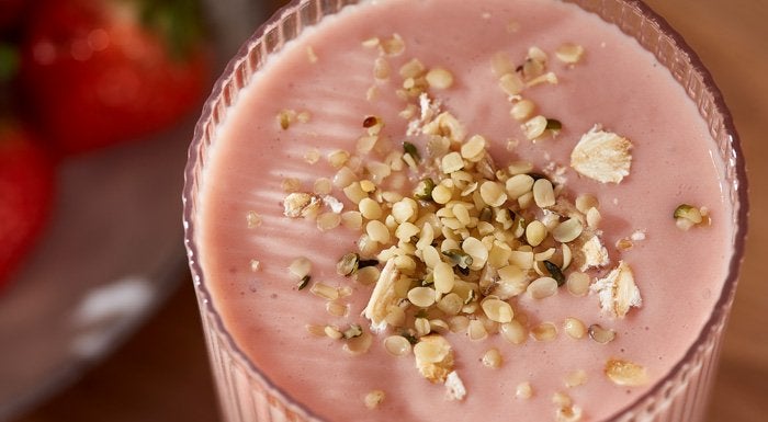 A fruit smoothie with oats and seeds sprinkled over the top.