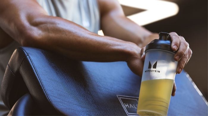 Person relaxing after a workout with a supplement shaker.