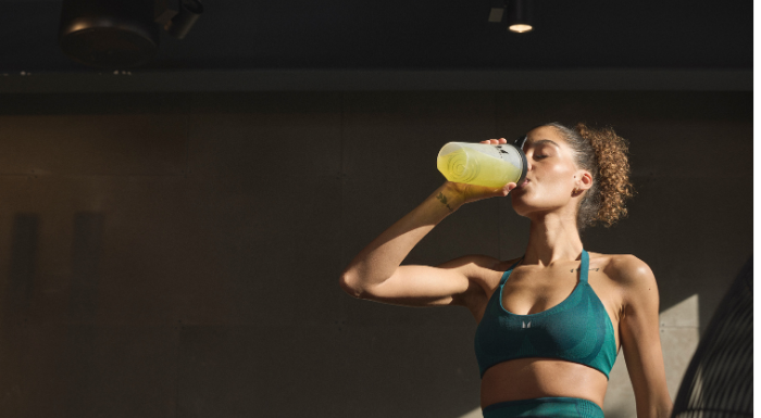 A girl in the gym refuelling with pre-workout.