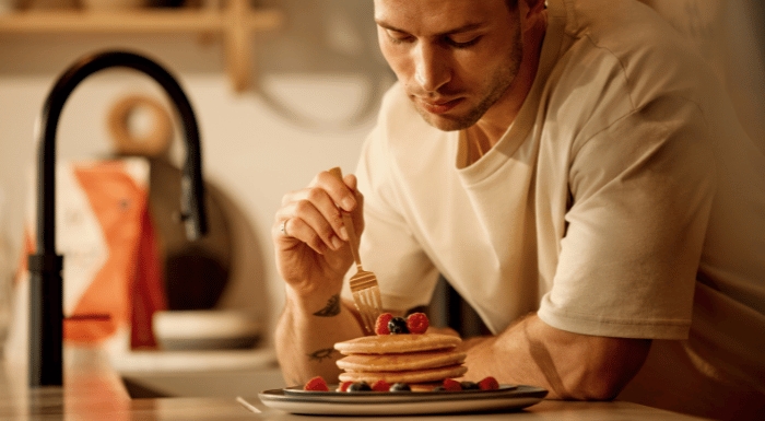 A man tucking into a stack of protein pancakes.